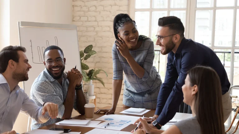 Happy friendly multiracial team laughing working together at corporate briefing